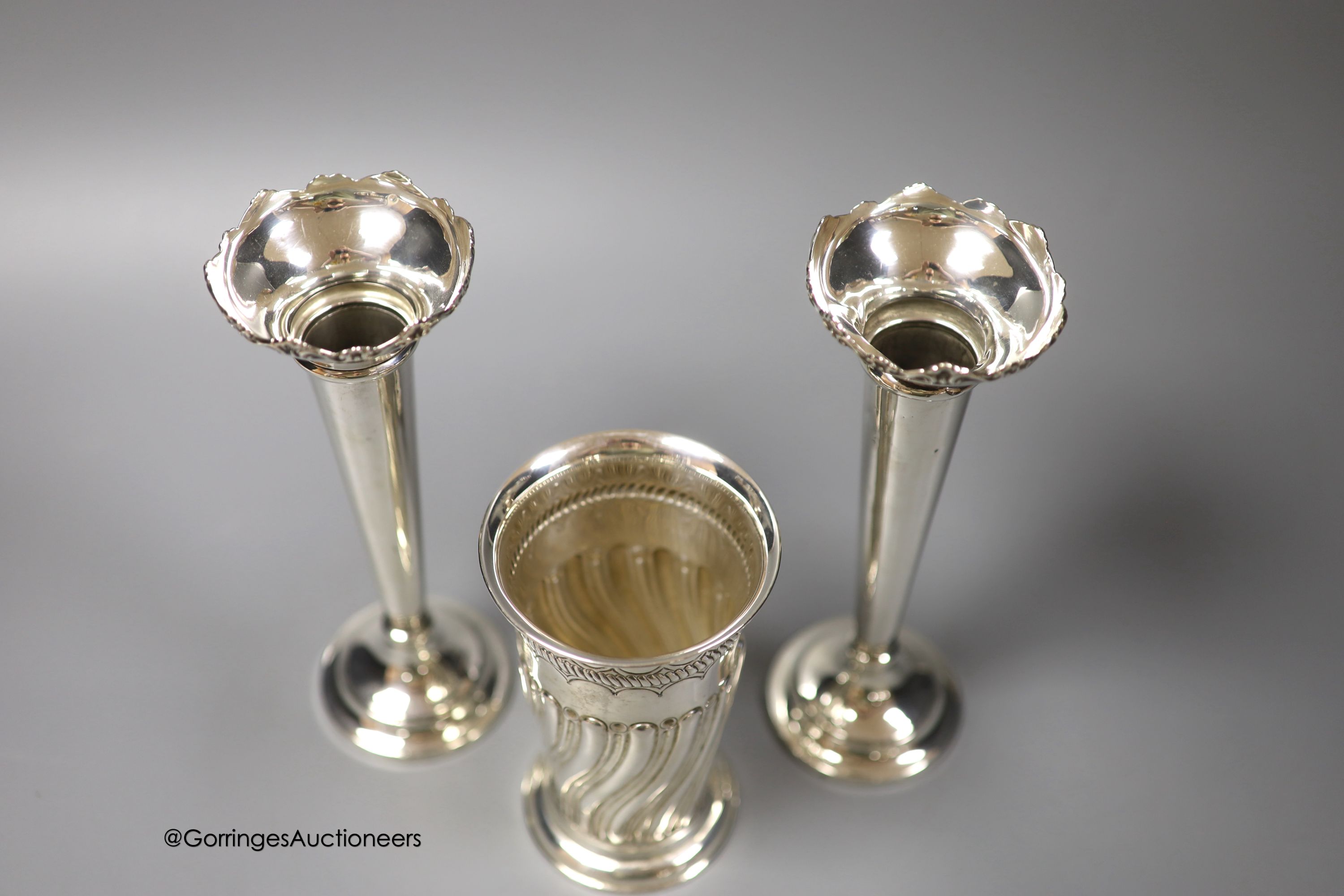 A late Victorian wrythened fluted silver vase, 13cm, 153 grams and a pair of later silver spill vases, 18.8cm, weighted.